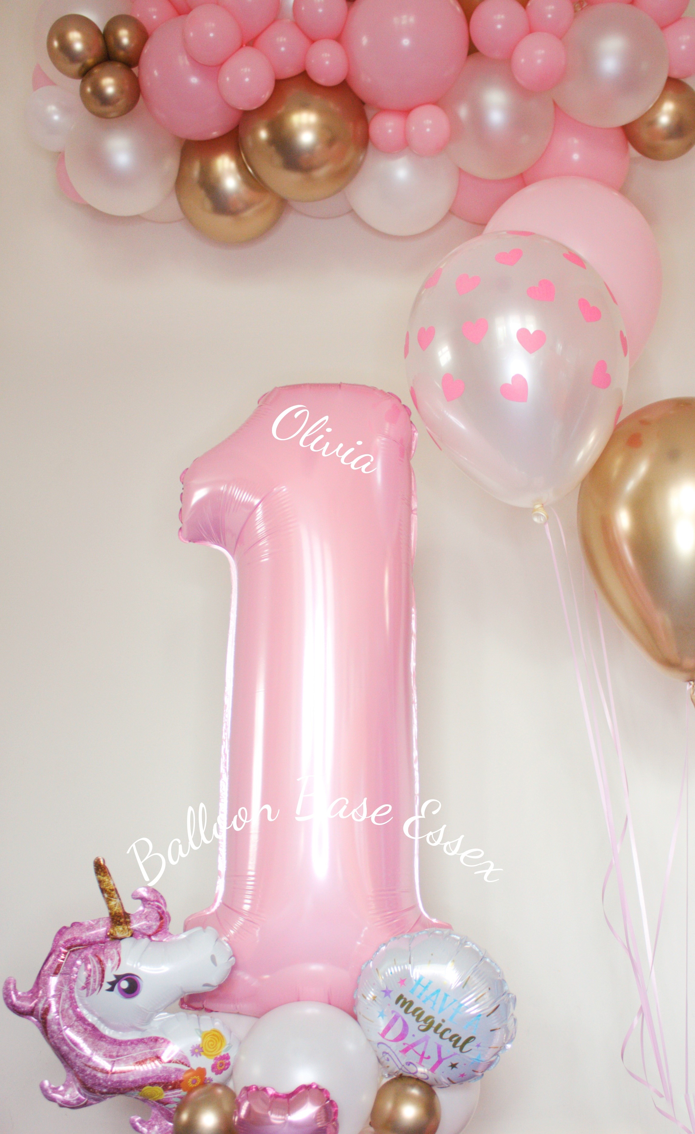 Pastel pink number 1 number on a pink unicorn themed balloon base with matching garland above and helium balloons