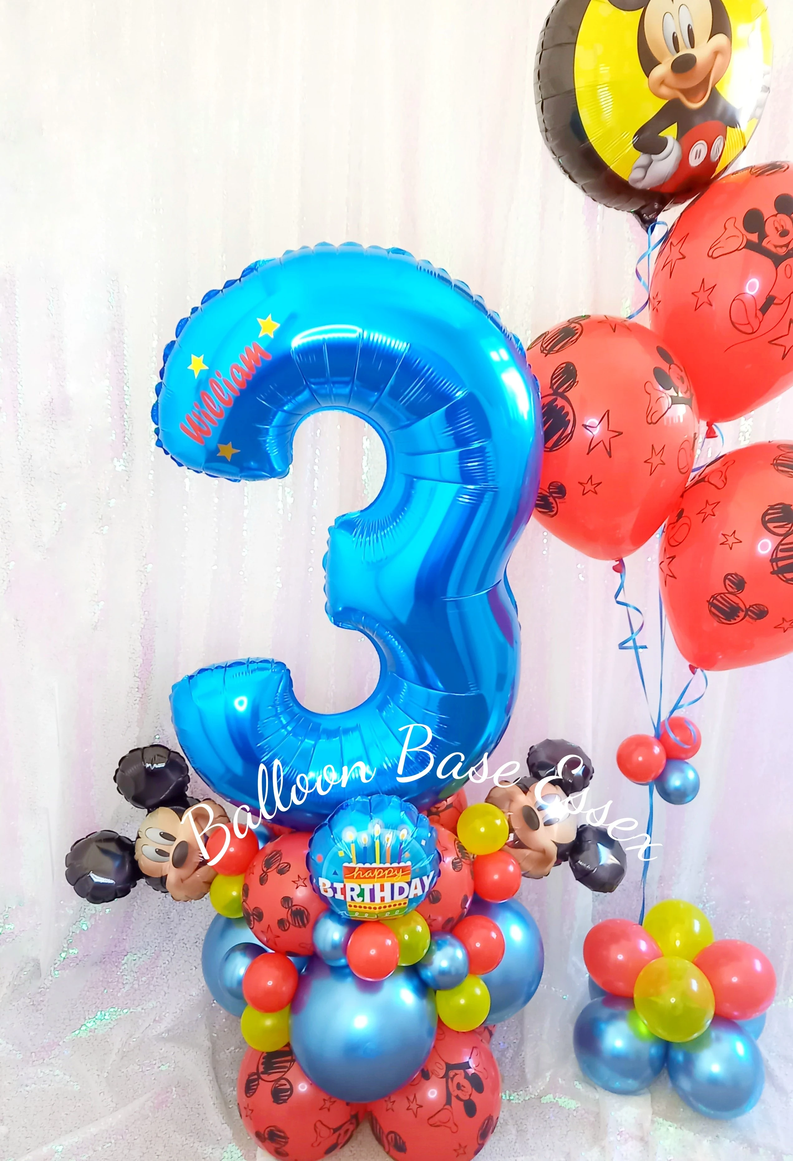 Mickey Mouse themed balloons in blue, red and yellow with a large blue number three balloon
