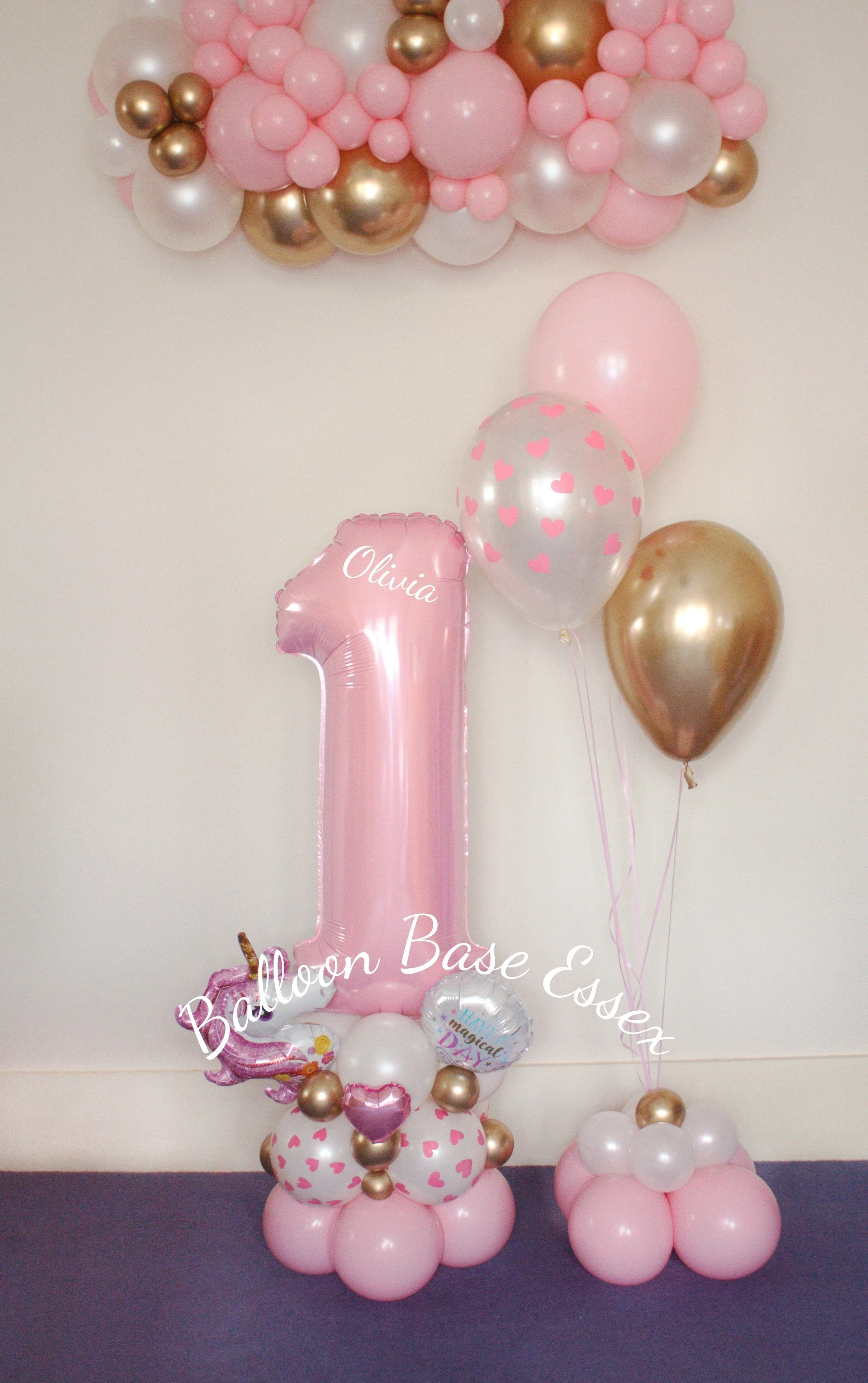 Pastel pink number 1 balloon stack with 3 helium balloons and balloon garland hanging above