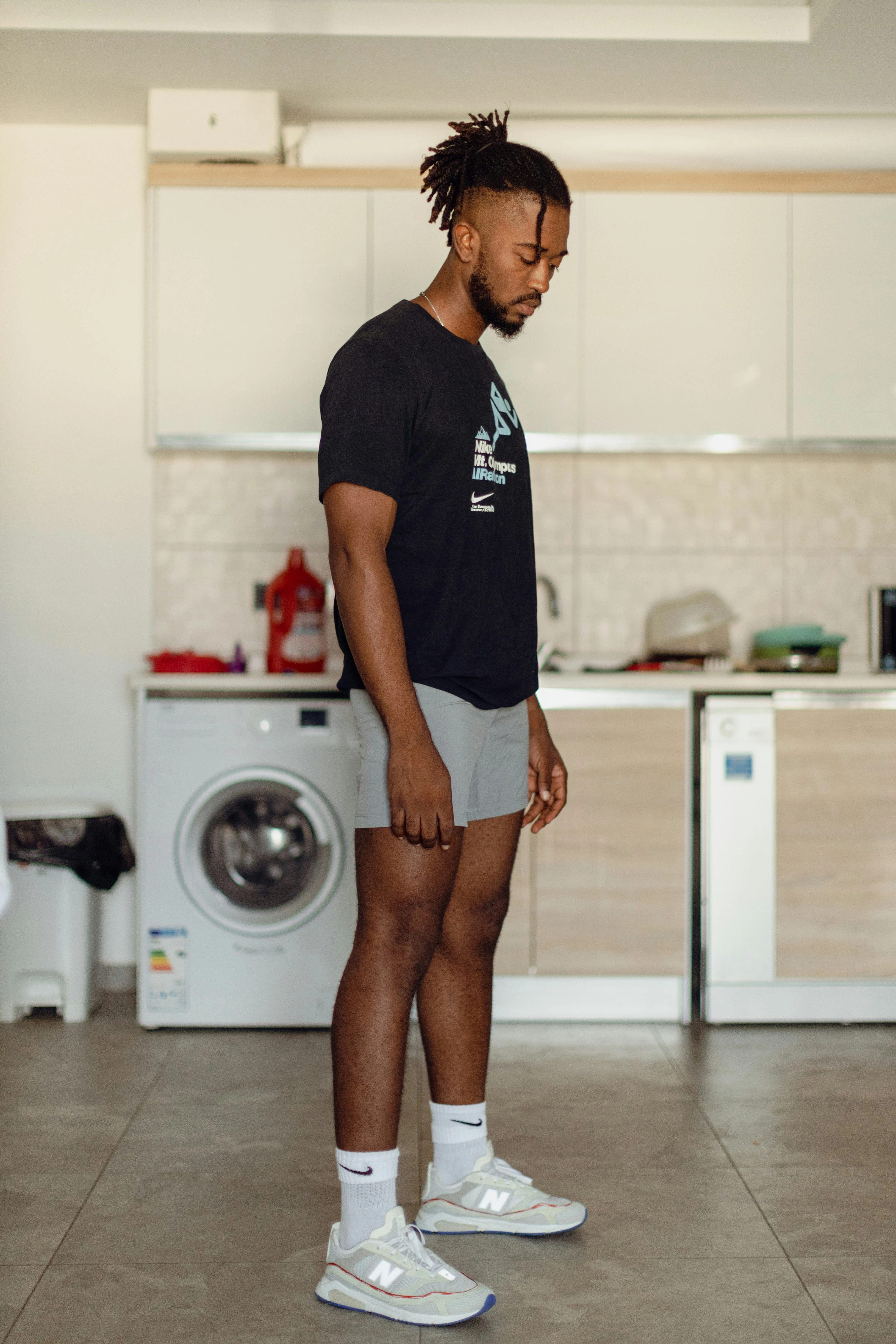 Young Black man in a kitchen wearing sportswear with a dejected look on his face