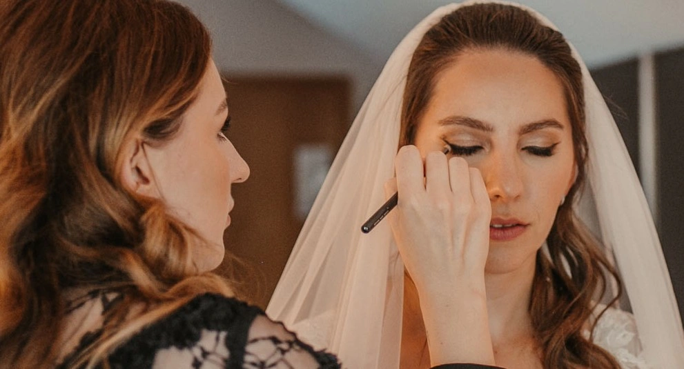 Braut mit Hochzeits Make-up, Schleier und gesteckter Brautfrisur wird geschminkt. Haare und Make-up von Denise Drahtmueller