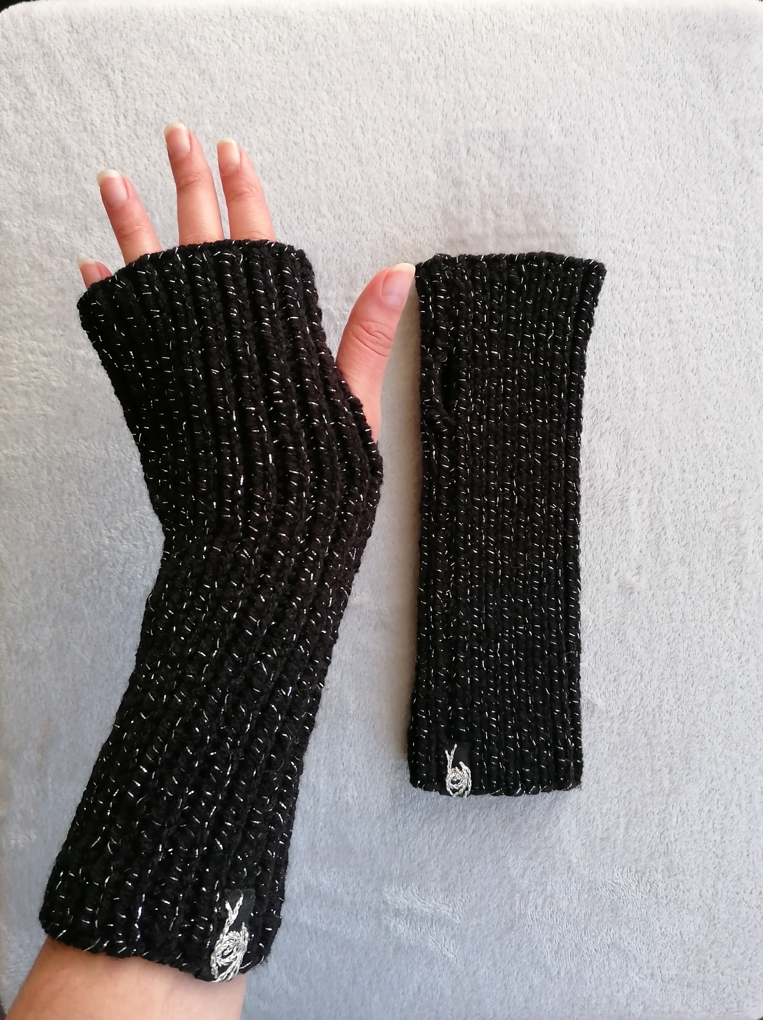 black glittery knitted fingerless gloves on grey background