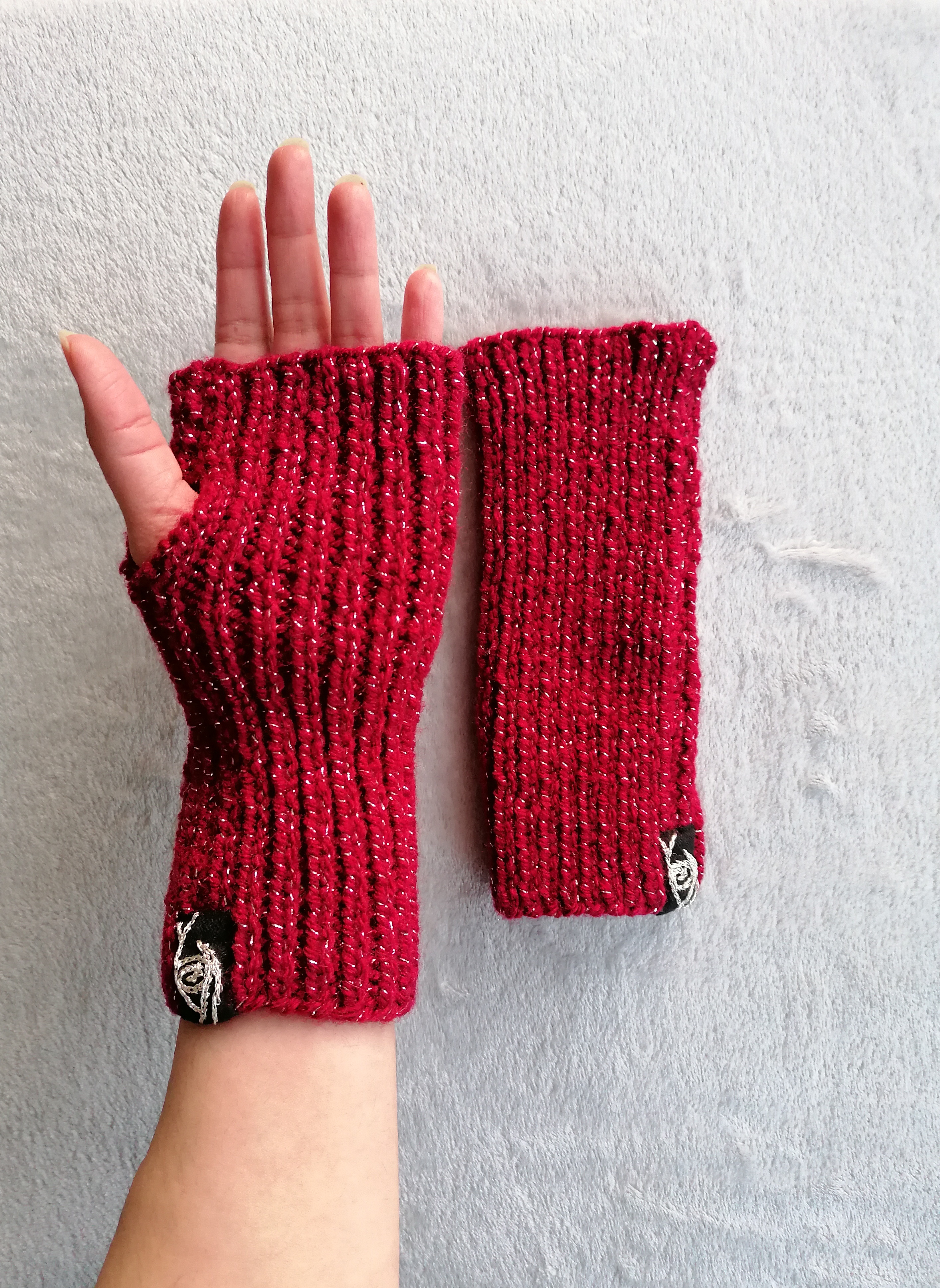 crimson glittery knitted fingerless gloves on grey background