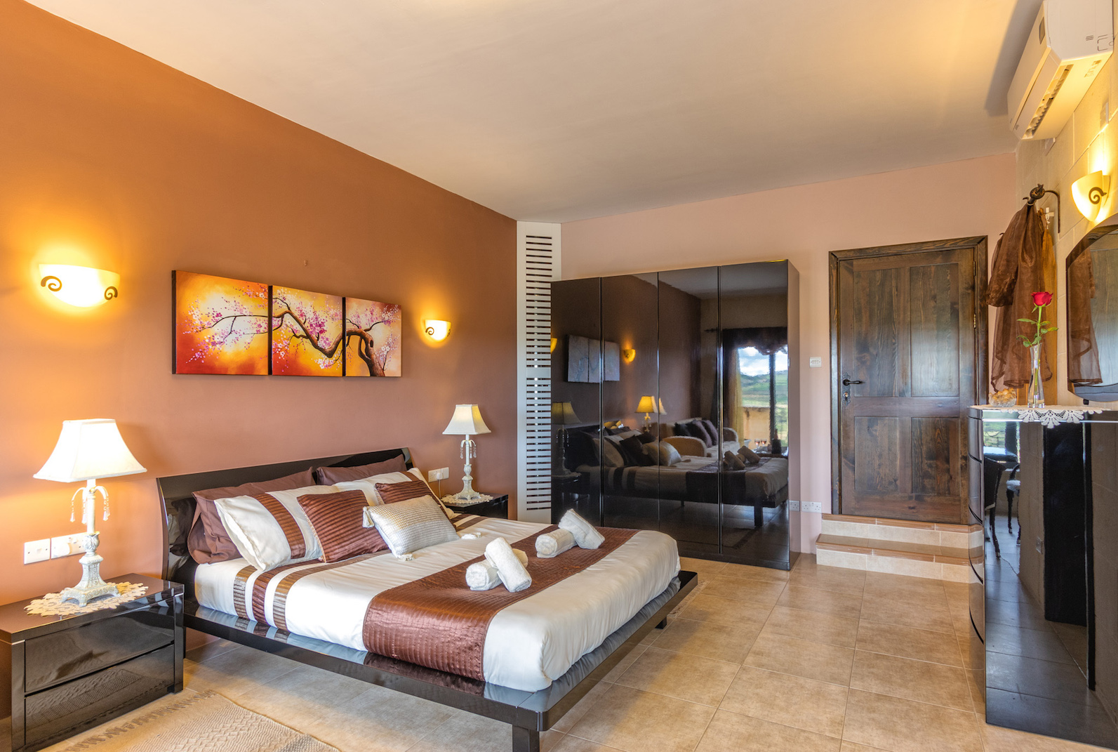 deluxe king suite bedroom with ensuite bathroom and terrace overlooking pool and country side views