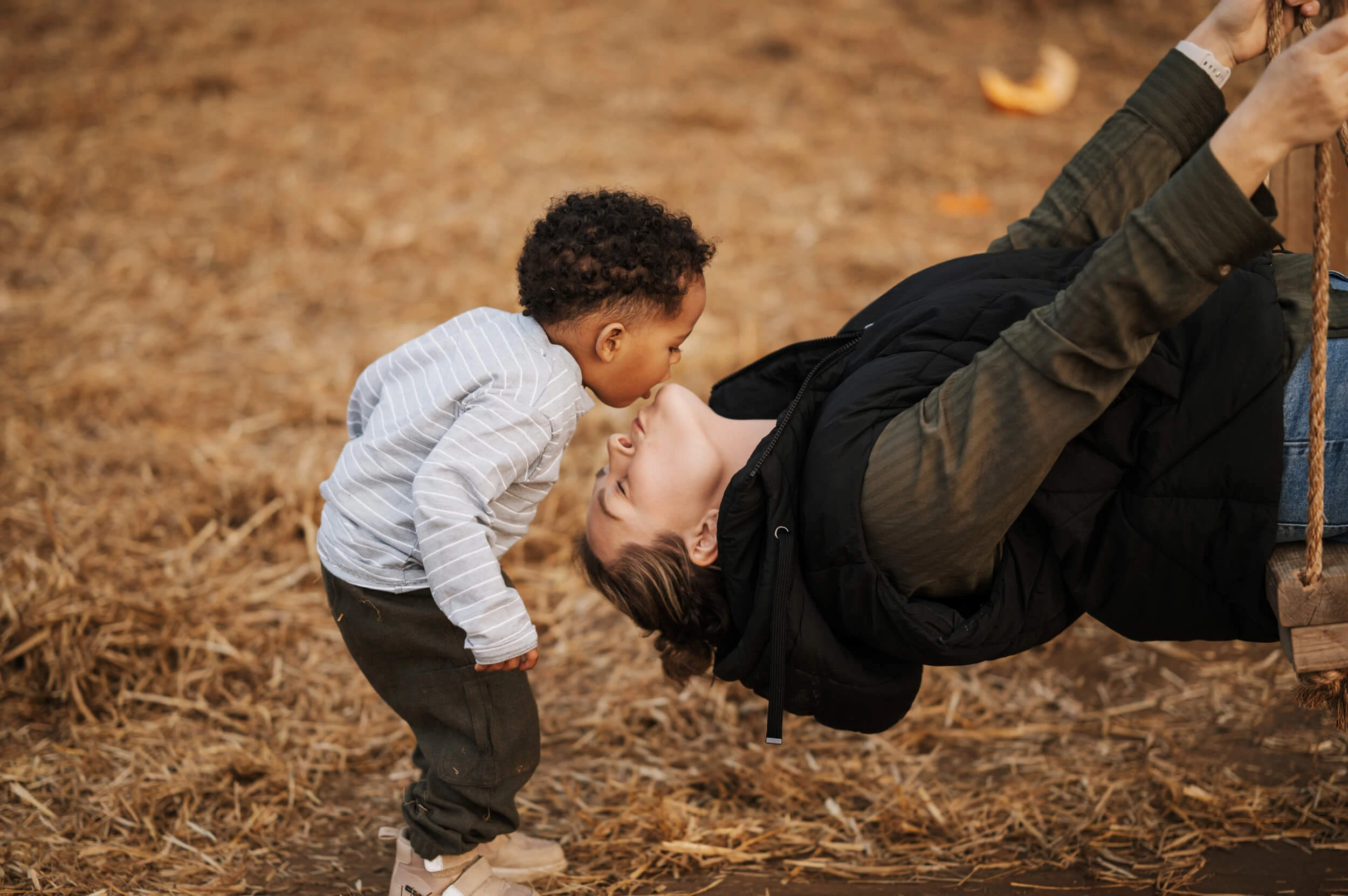 Son giving mum a kiss while playing on a swing