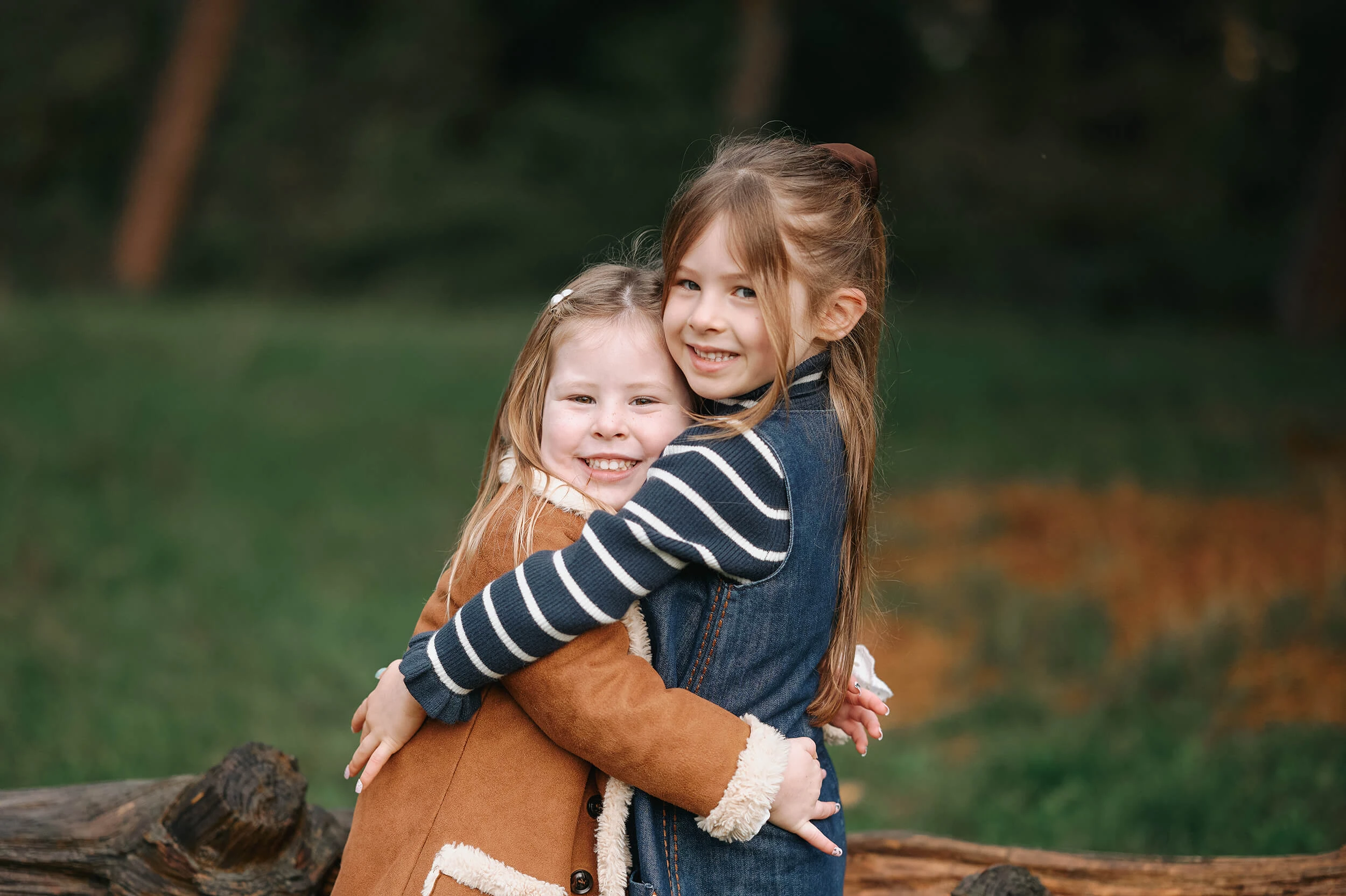 Sisters cuddling and smiling in autumnal photoshoot outdoors