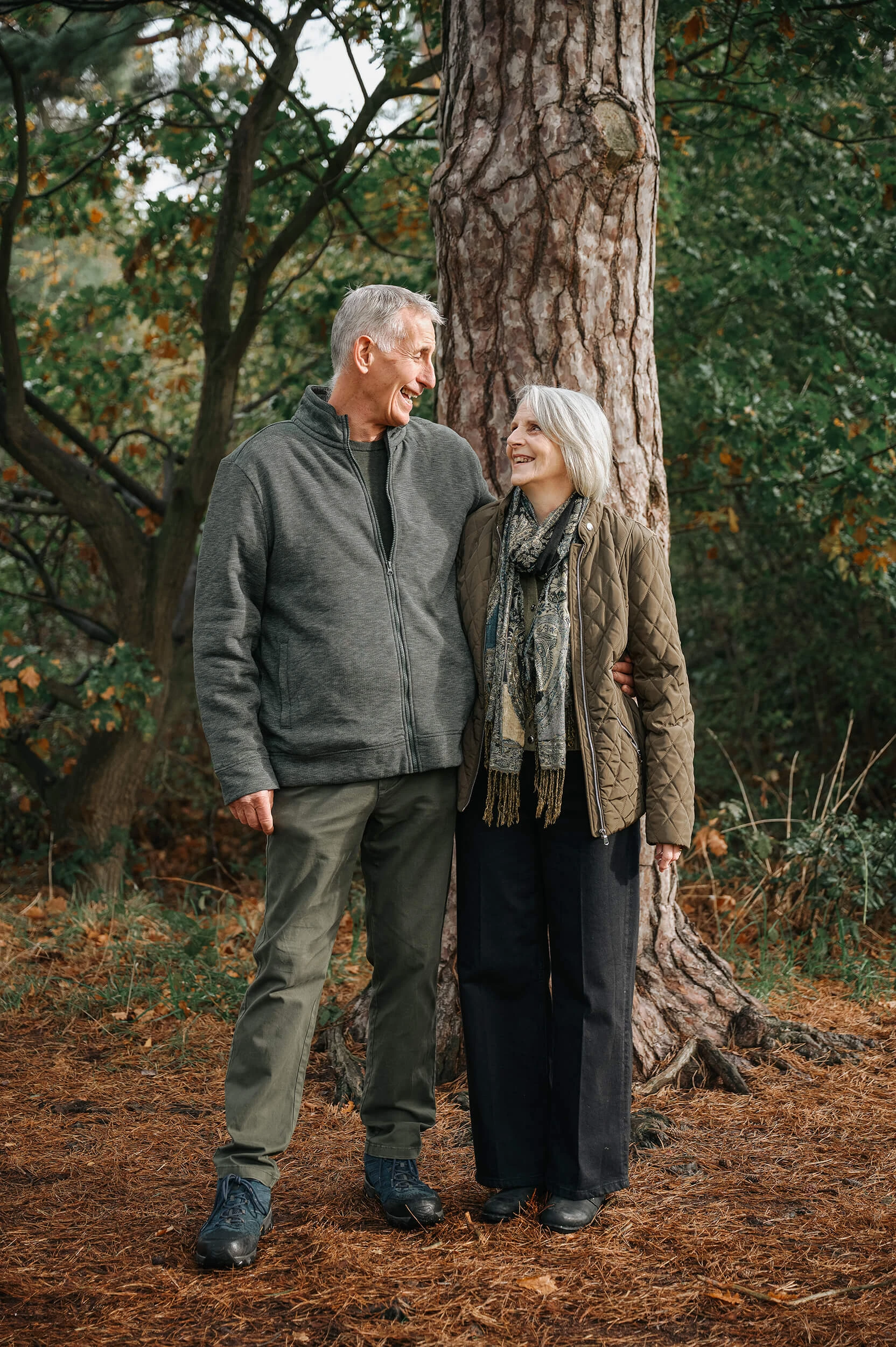 Mature couple smiling and laughing under trees 