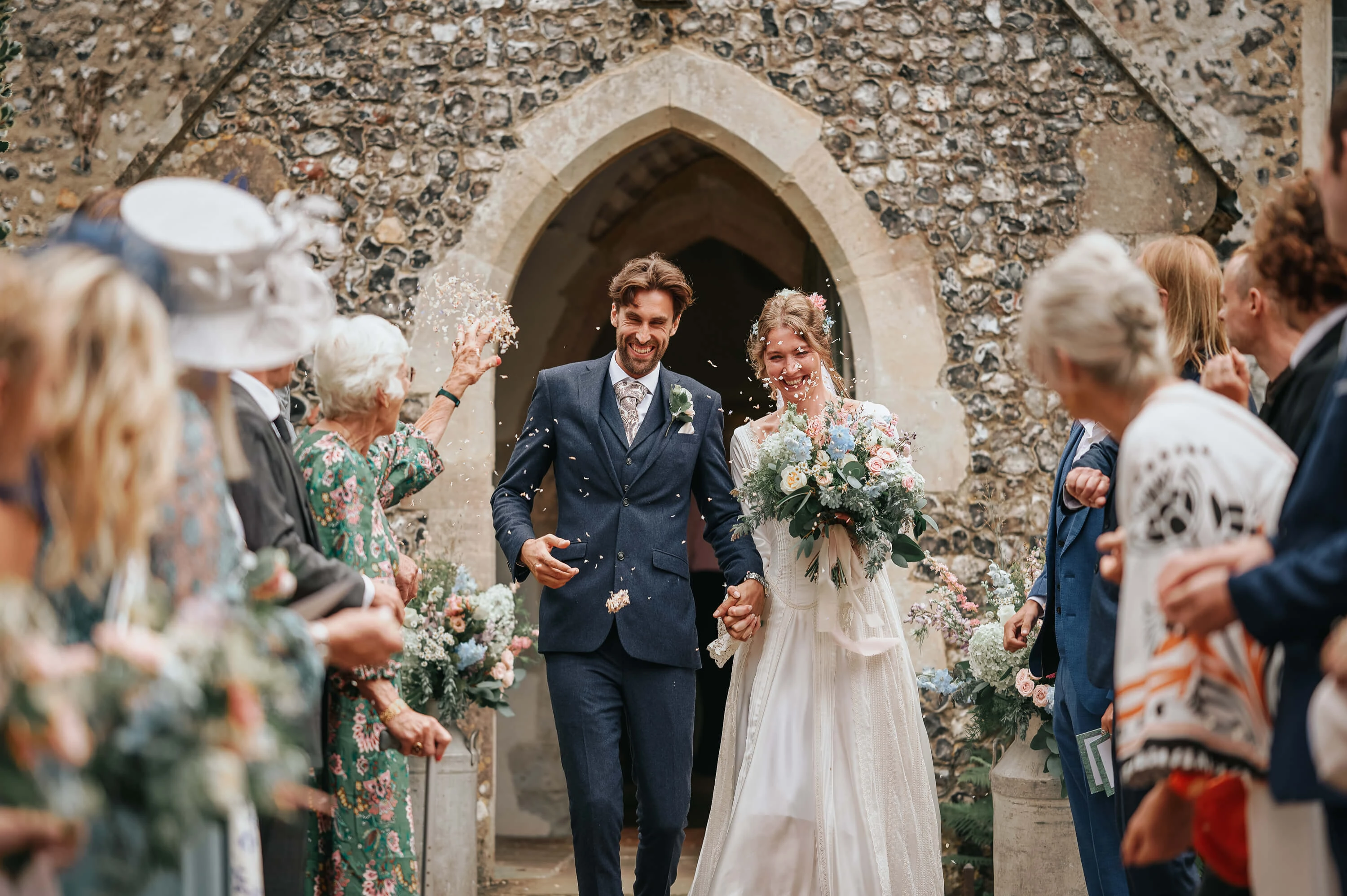 Bride and groom walking through confetti after the ceremony in Canterbury