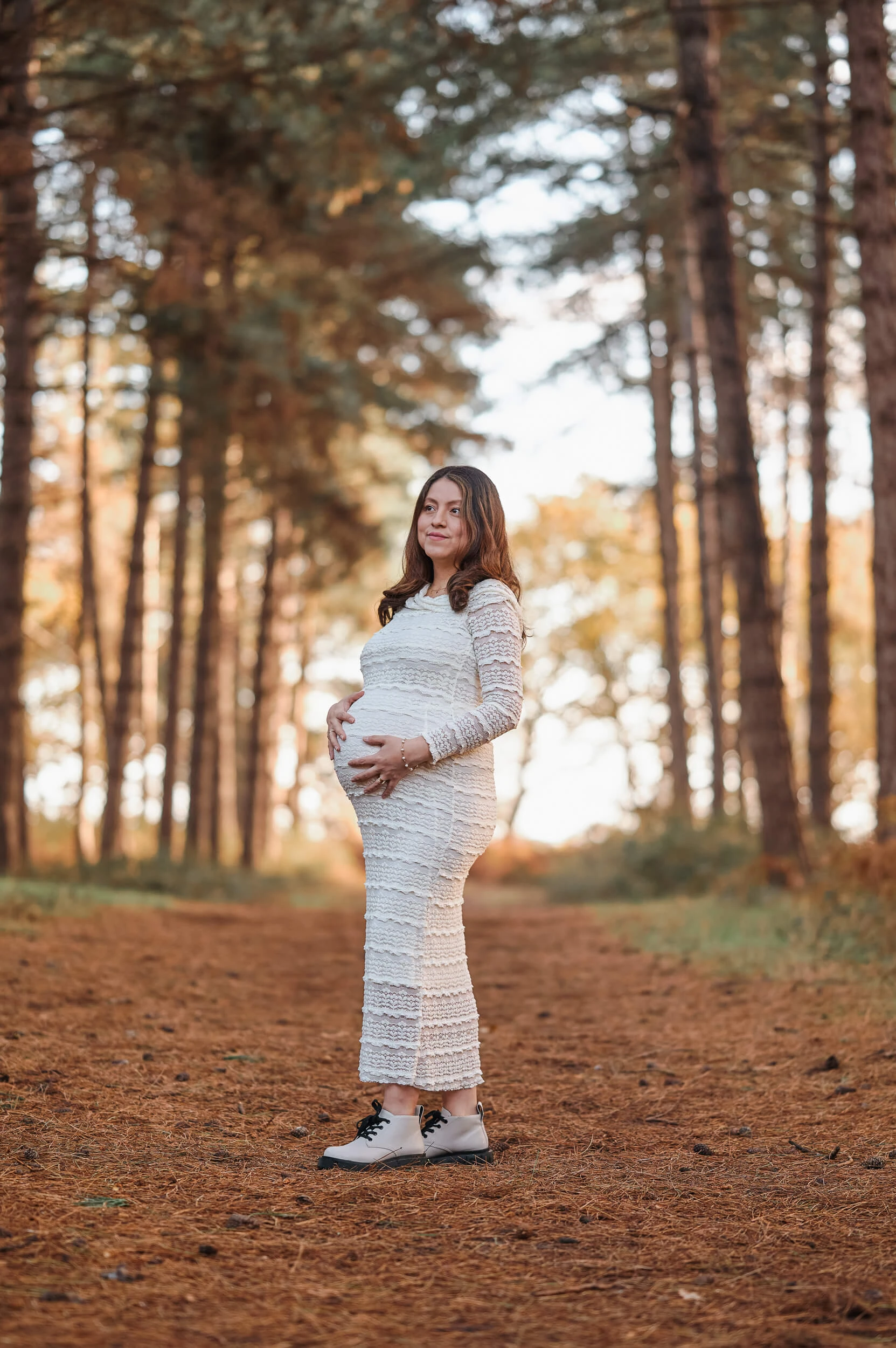 maternity photo shoot under tall trees in winter