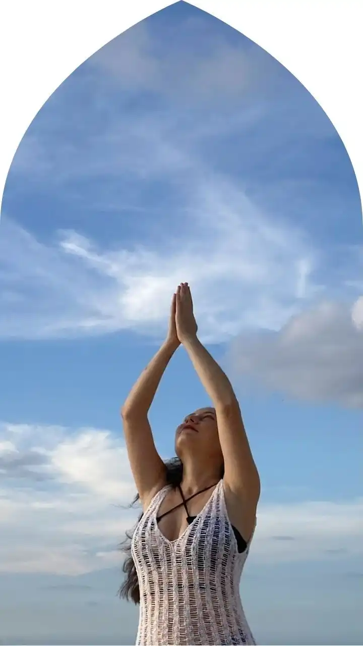 Prayer pose beneath Bali’s infinite sky Carla with prayer hands lifted toward the sky, embodying spiritual presence during a Bali retreat.