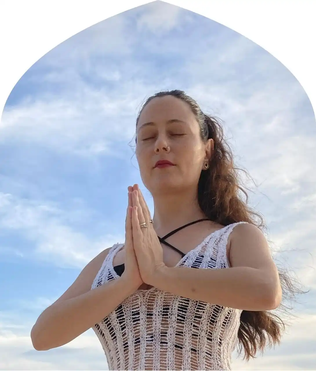 Mindful Meditation at a Bali Retreat – Carla in Tropical Serenity Carla in a prayer pose beneath an open sky during a Bali retreat ceremony, inviting reflection and connection.