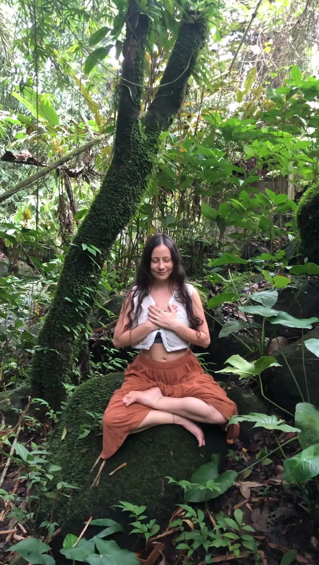 Carla in a prayer pose beneath an open sky during a Bali retreat ceremony, inviting reflection and connection.