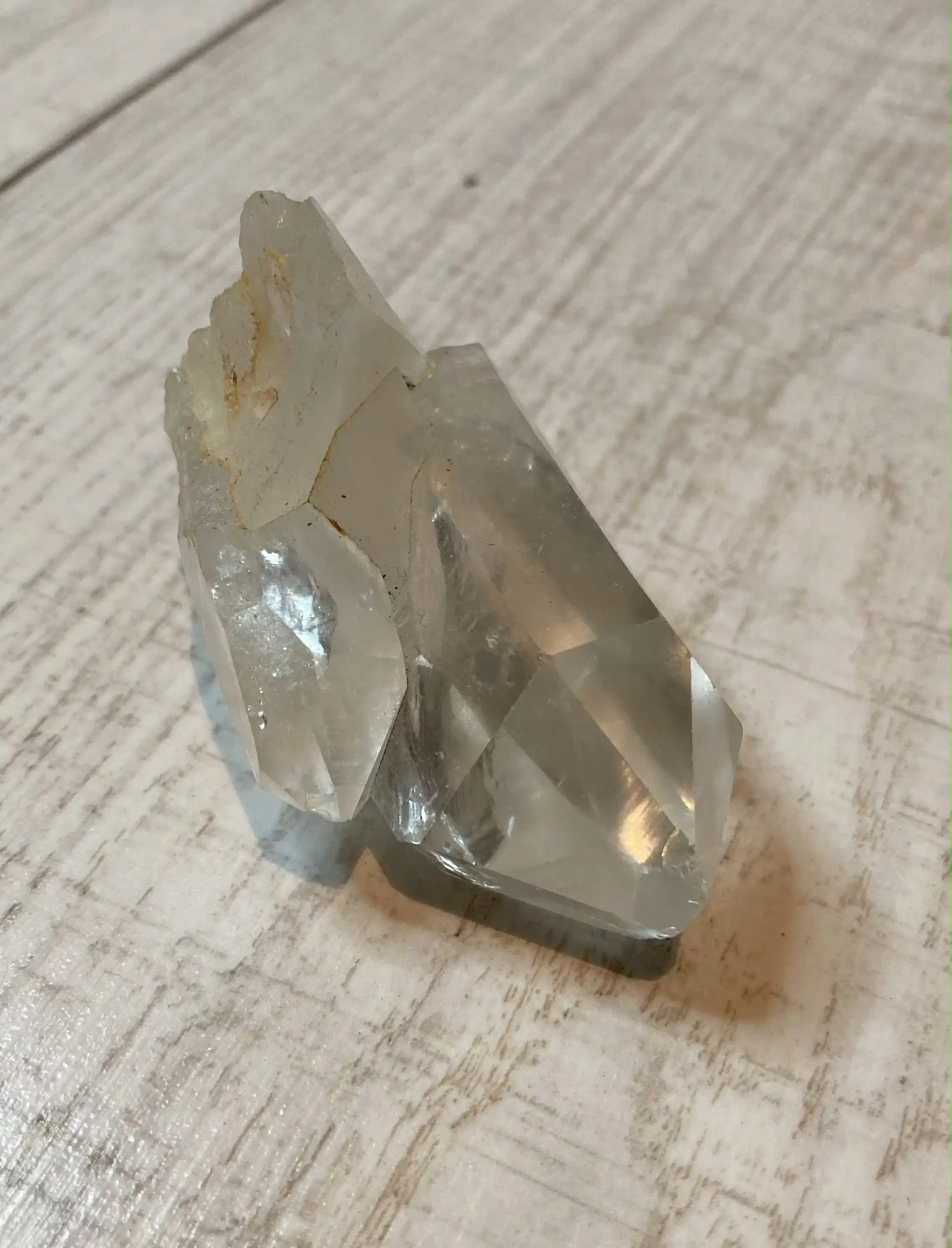 Clear quartz crystal cluster on a wooden background, representing spiritual clarity, energy amplification, and truth.