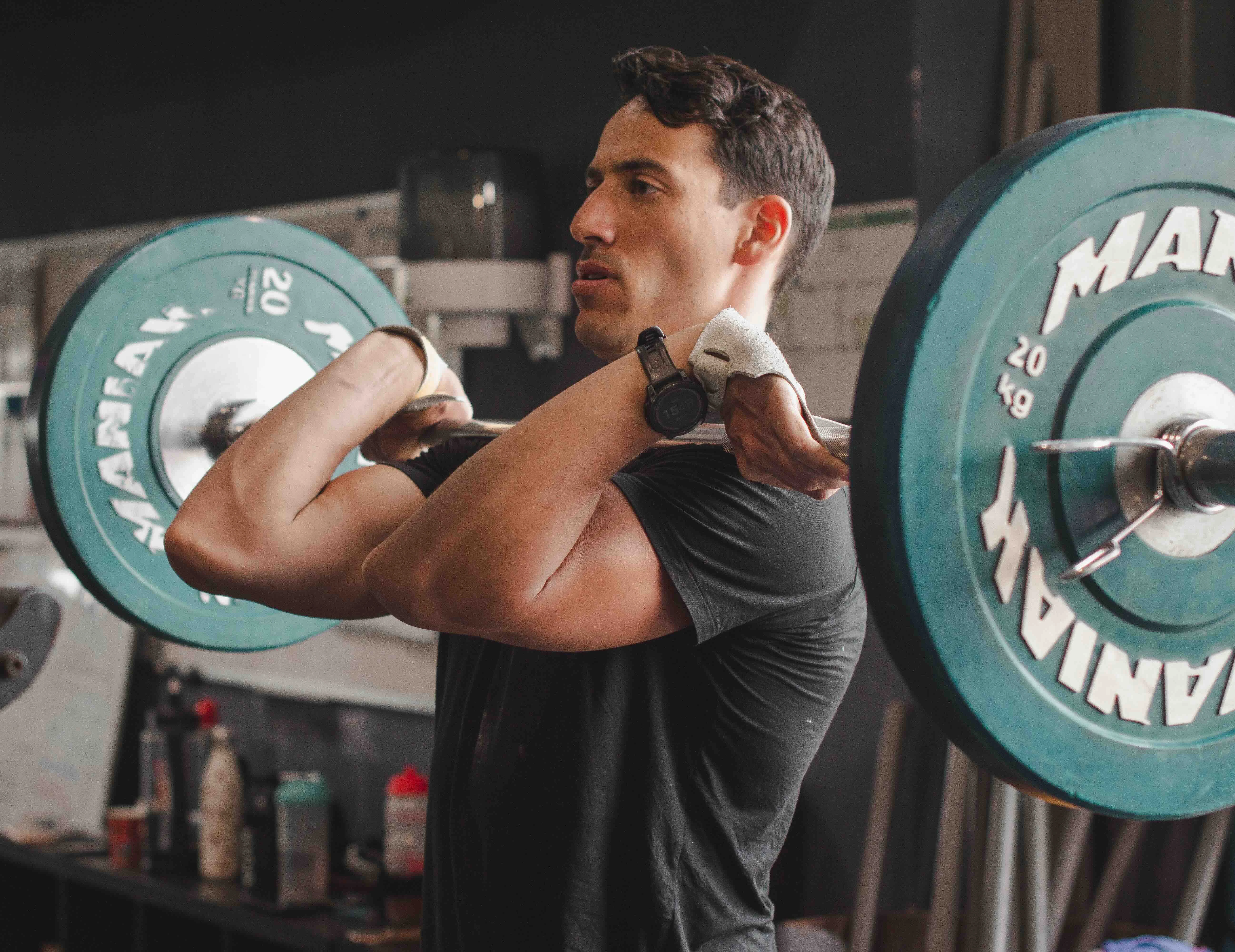 A focused individual performing a barbell squat at a crossfit gym with weight plates on the barbell.