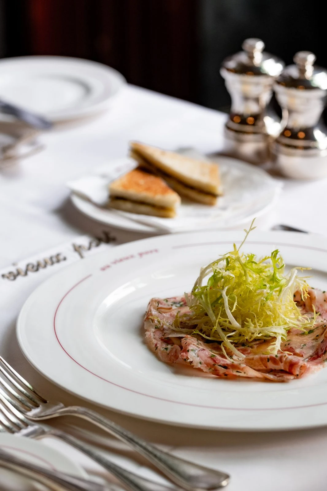 Voorgerecht met frisée en toast op een bord met gouden boord