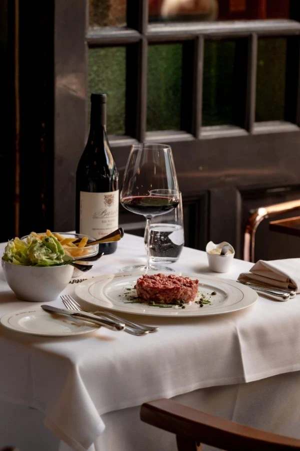 Gedekte tafel met een glas rode wijn en steak tartaar met salade