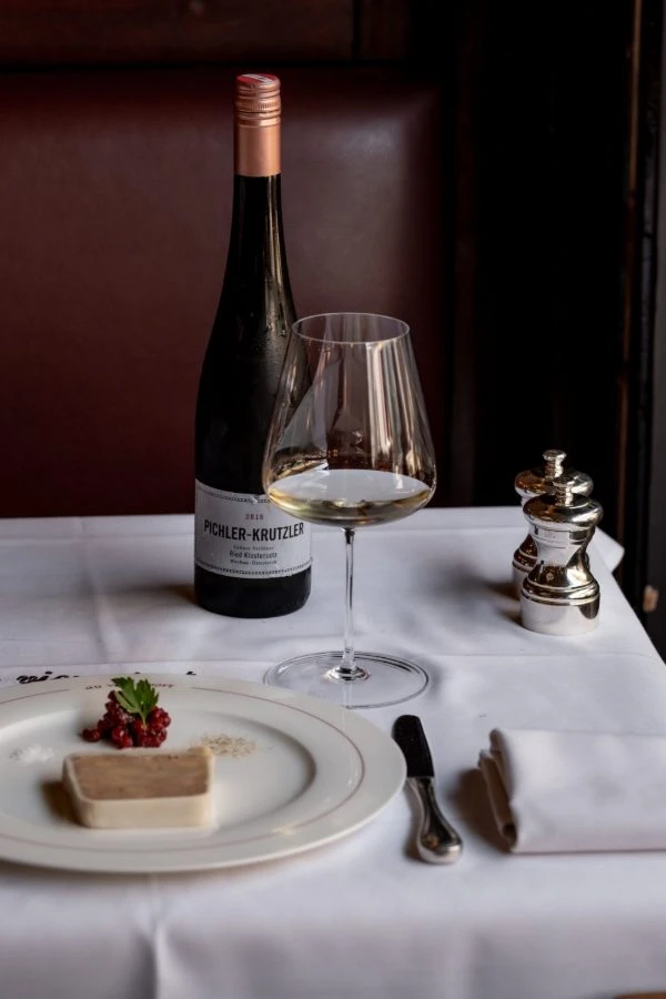 Paté met een glas witte wijn op een gedekte tafel
