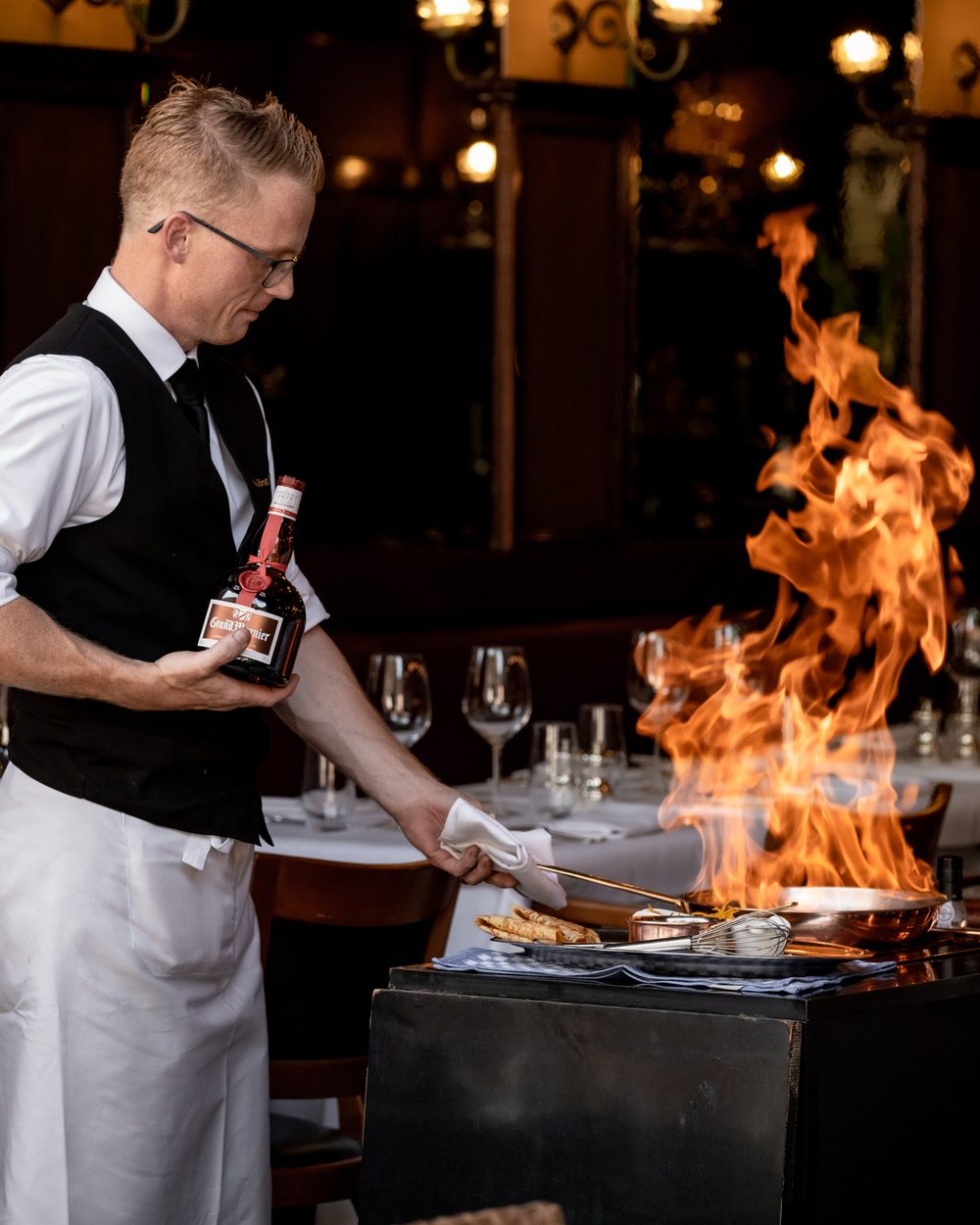 Kelner die crêpes Suzette flambeert met Grand Marnier